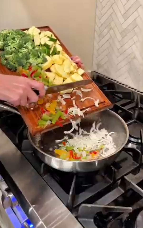 Faceless cooking content showing fresh vegetables being added to a skillet